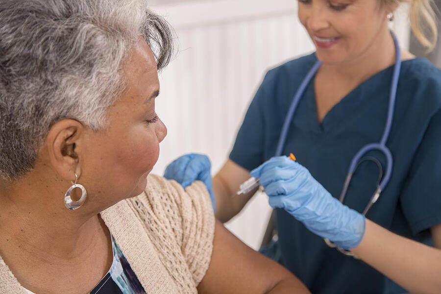 Nurse gives flu vaccine to senior adult patient at clinic. #5 Photograph by Fstop123