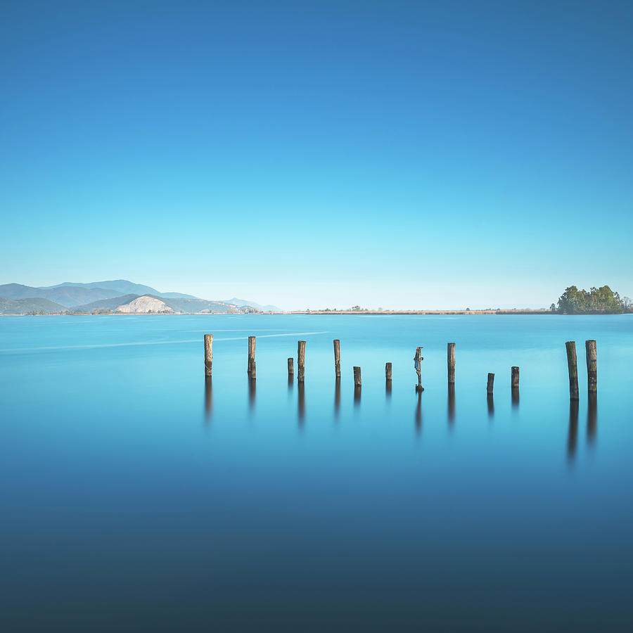 Wooden pier or jetty remains on a blue lake sunset and sky refle #5 Photograph by Stefano Orazzini