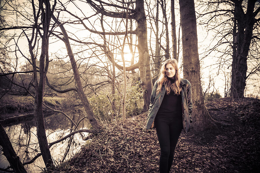Beautiful young woman in black walking by a river #6 Photograph by Theasis