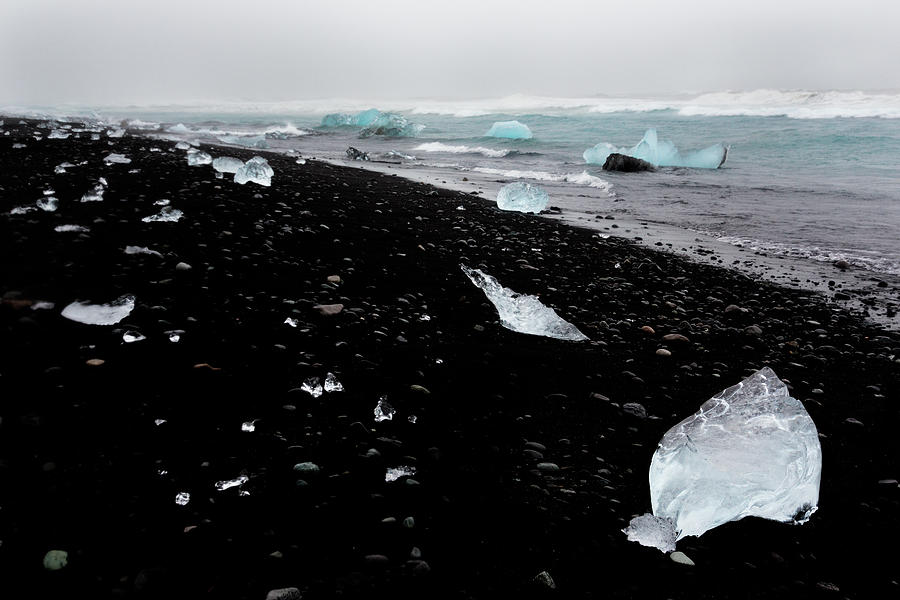 Glistening chunks of ice wash up on a lava black sand beach in t #6  Photograph by Bruce Beck - Pixels