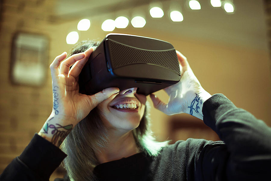 Young woman looks fascinated into Virtual Reality Headset #6 Photograph by Marco_Piunti