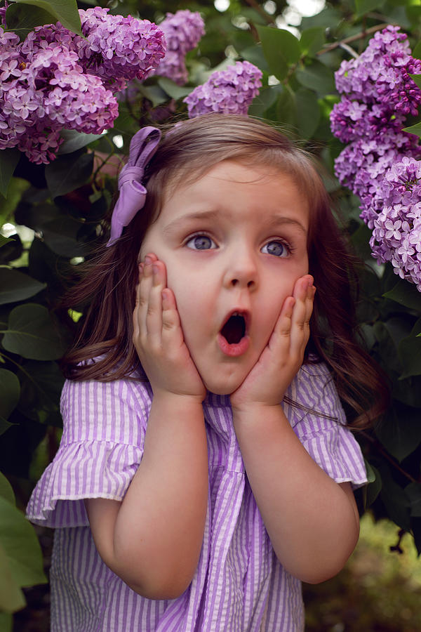 Three Year Old Girl Stands In Lilac Bushes In A Dress And A Bow 8824