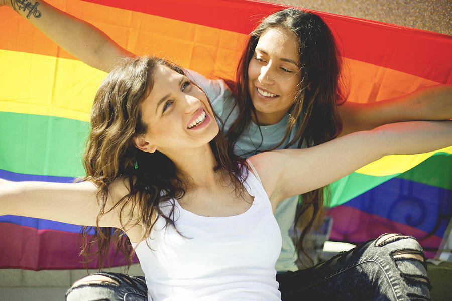 LGBT Lesbian couple moments happiness concept. Holding rainbow flag outdoors #8 Photograph by MarijaRadovic