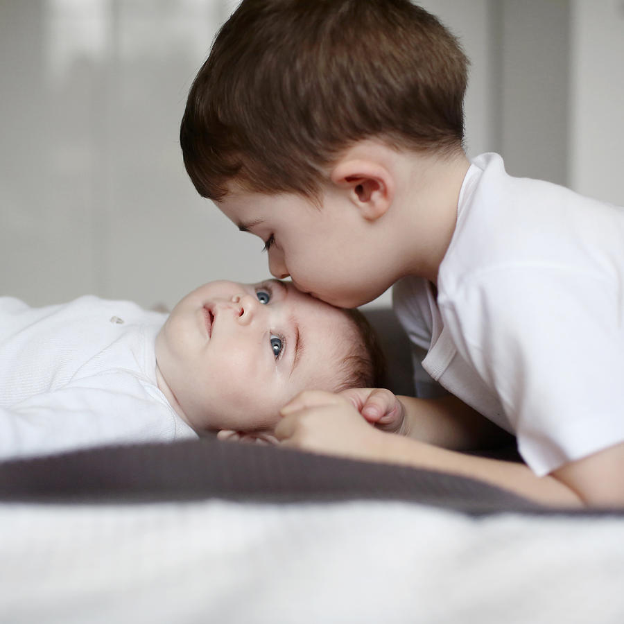 A 3 years old boy kissing his baby brother Photograph by Catherine Delahaye