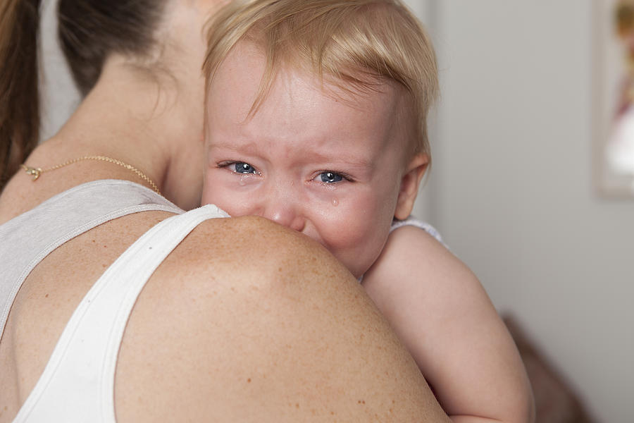 A baby crying and leaning on her mothers shoulder Photograph by Carey Kirkella