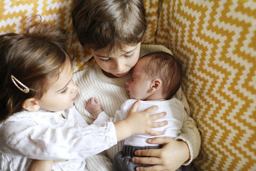 A baby in the arms of his big brother and sister Photograph by Catherine Delahaye