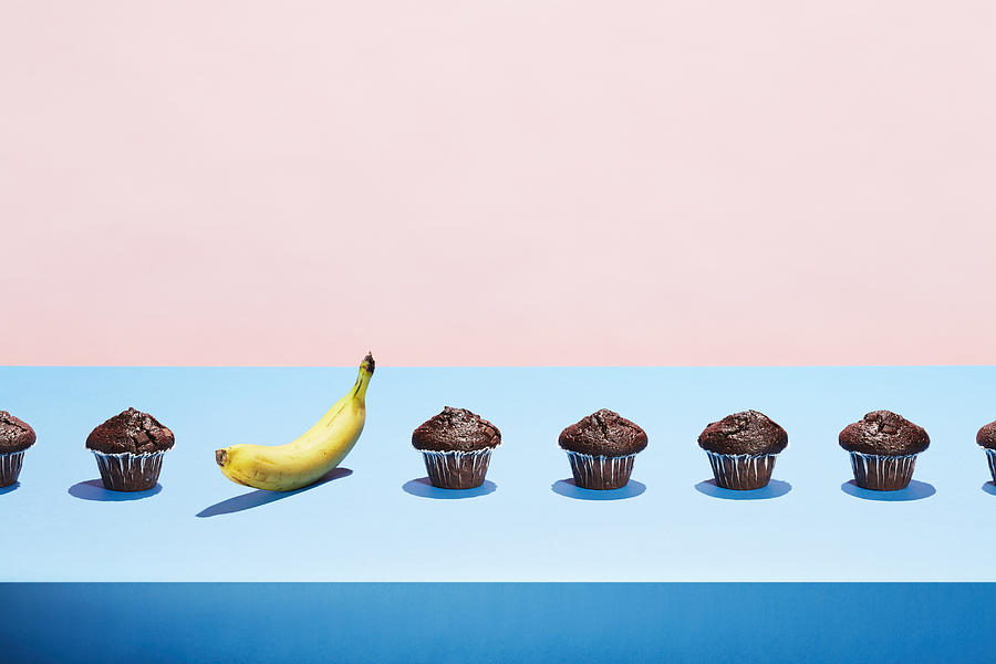 A banana in a row of chocolate cupcakes Photograph by Richard Drury