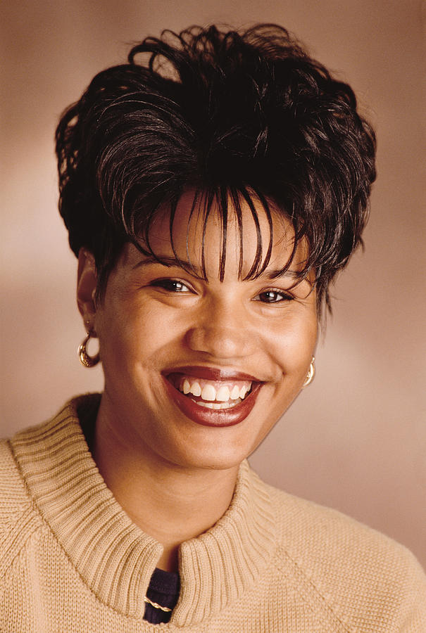 A Beautiful Happy African American Woman In A Tan Sweater Laughs And Smiles For The Camera Photograph by Photodisc