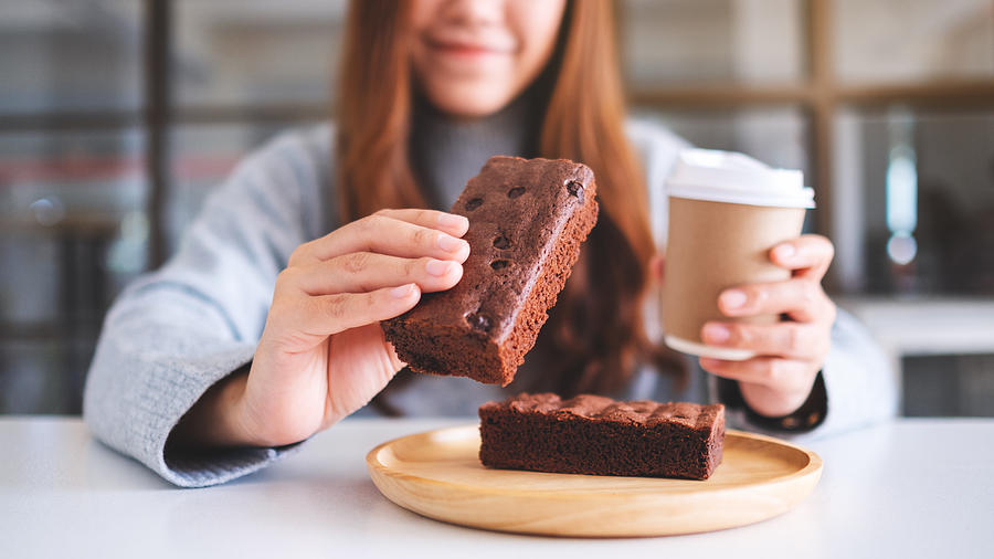 A Beautiful Woman Holding And Eating A Piece Of Brownie Cake While Drinking Coffee Photograph by Farknot_Architect