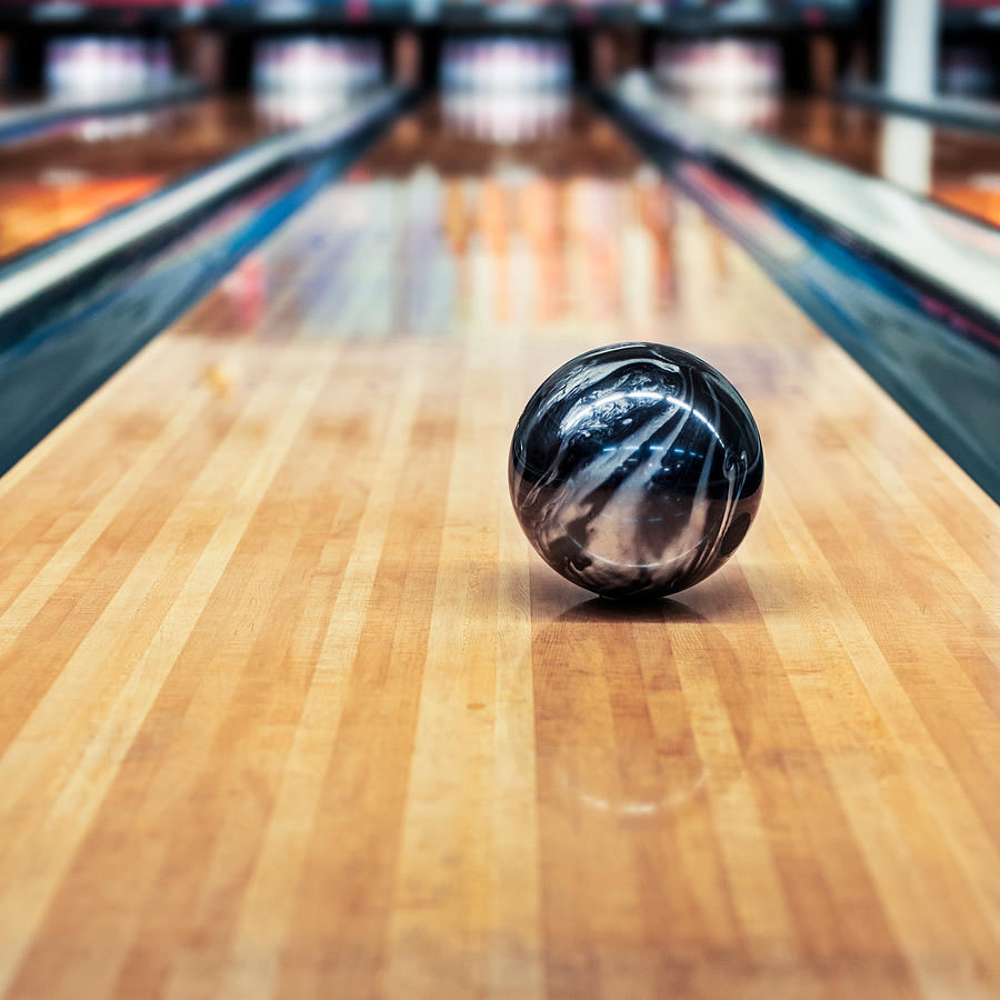 A black and silver bowling ball rolling down the lane Photograph by Lkpgfoto