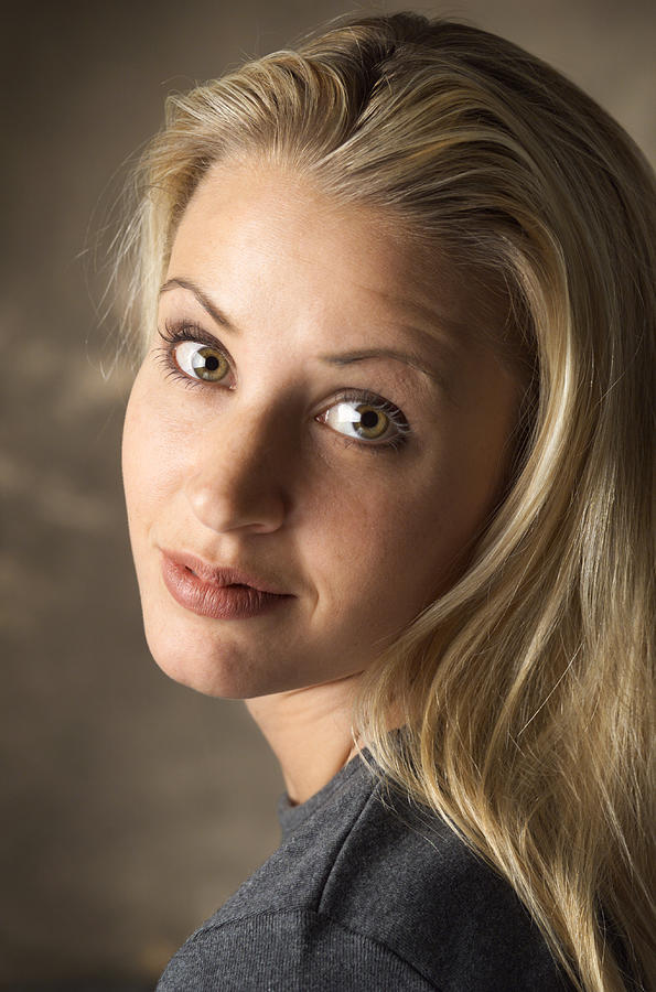 A Blond Caucasian Woman In A Gray T-shirt Is Looking Over Her Shoulder At The Camera As She Grins Photograph by Photodisc