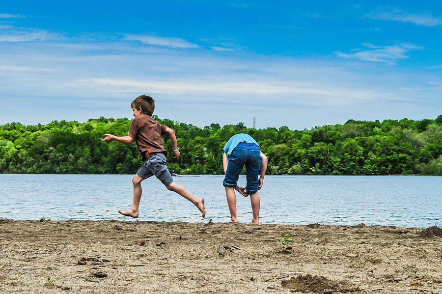 A boy runs by a girl at the waters edge at Hueston Woods State Park OH. Photograph by Molly Steinwald
