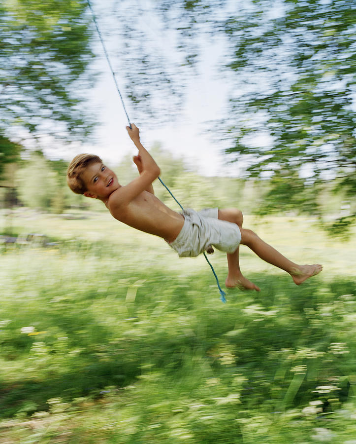A boy swinging in a green garden. Photograph by Per Eriksson