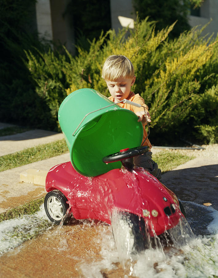 A boy washing a red car. Photograph by Per Eriksson
