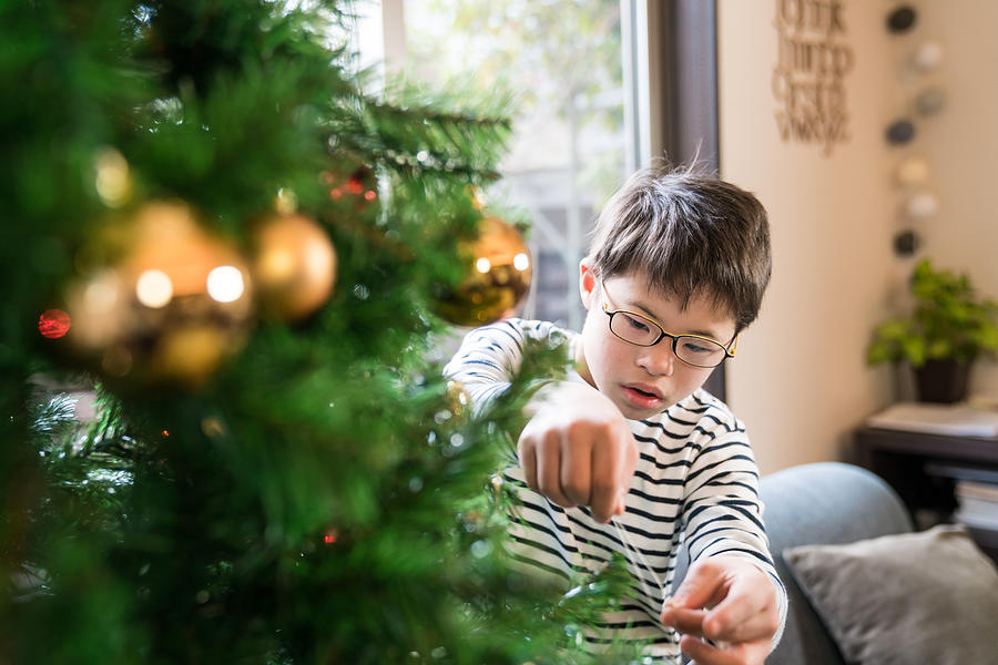 A boy with Downs syndrome decorates a Christmas tree Photograph by Tdub303