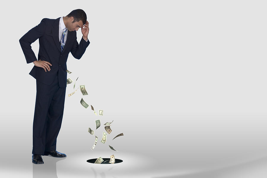 A businessman losing his money down the drain Photograph by Comstock Images