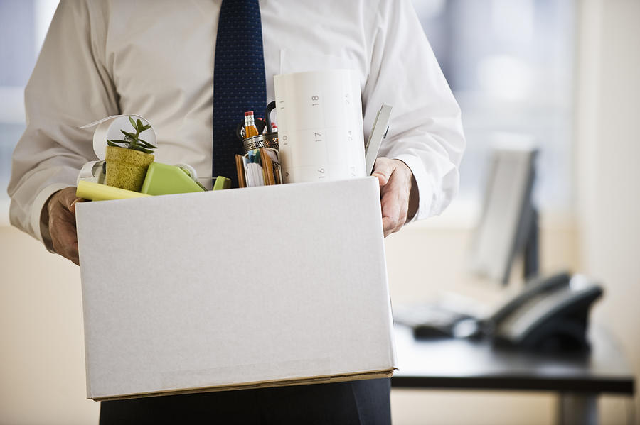 A businessman with a box full of desk stuff Photograph by Tetra Images - Daniel Grill