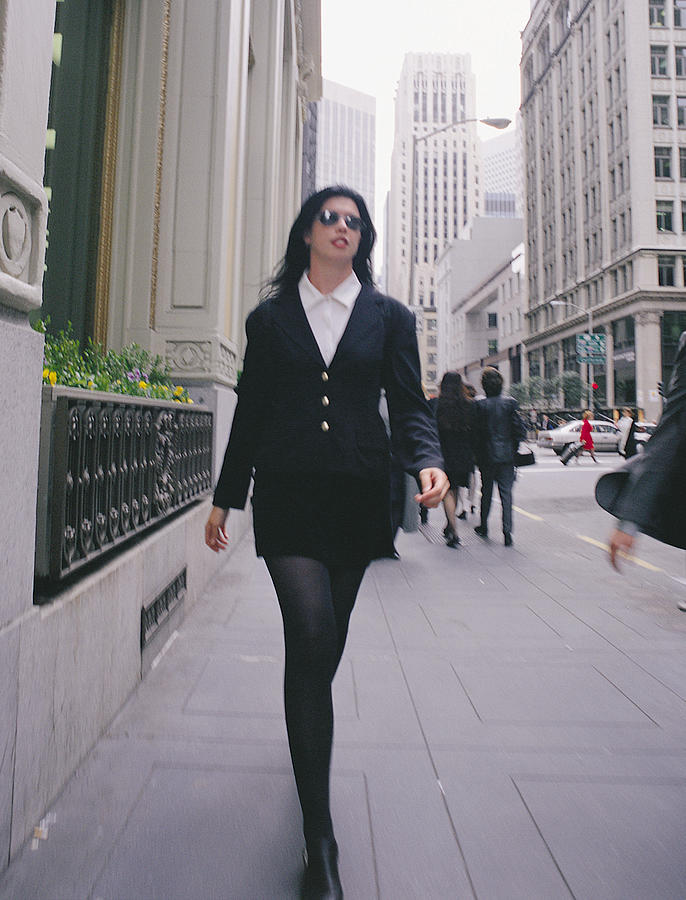 A Businesswoman In A Black Miniskirt And Sunglasses Walks On A Side Walk In A City Photograph by Photodisc