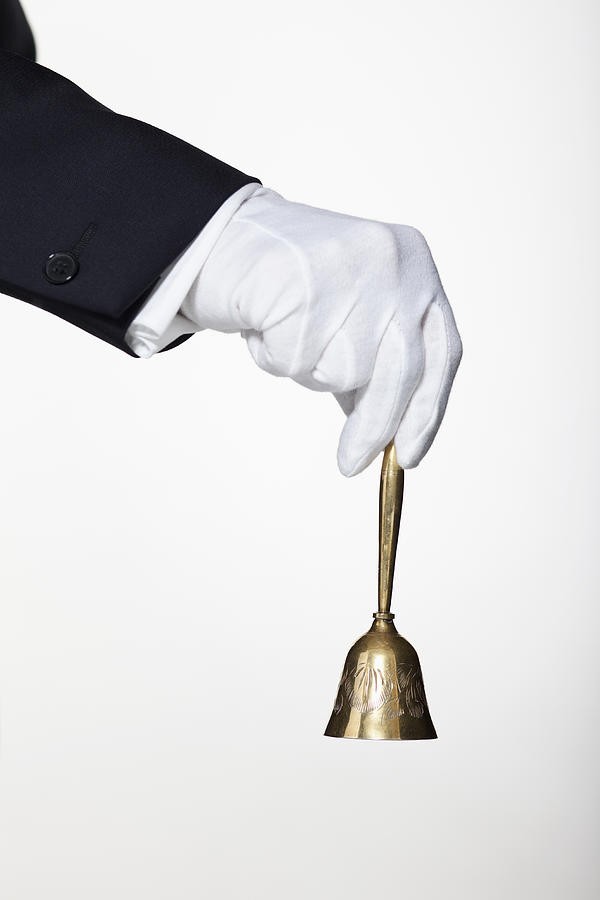 A butler ringing a hand bell for service, focus on hand Photograph by Hudzilla