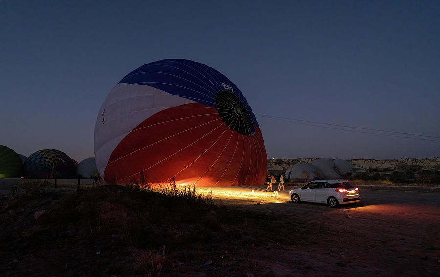 A car parked in front of a hot air balloon with headlights on during night, preparation of a flight in Goreme national park in Cappadocia, Turkey Photograph by Arpan Bhatia