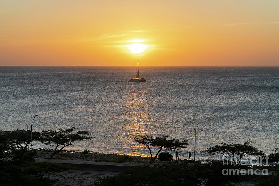 A catamaran sailboat glides through the sunset near Eagle Beach  Photograph by William Kuta