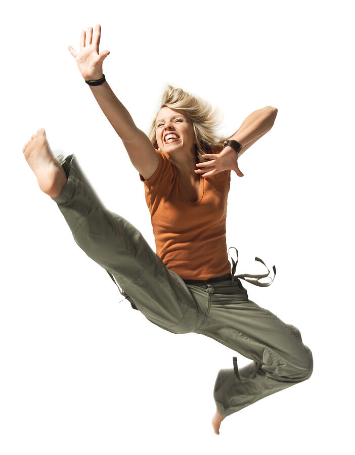 A Caucasian Blonde Female Teen In Green Pants And An Orange Shirt Jumps Up In The Air Photograph by Photodisc