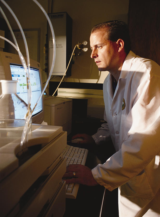 A Caucasian Chemist Analyzes Data On A Computer Screen While Standing In A Laboratory Photograph by Photodisc