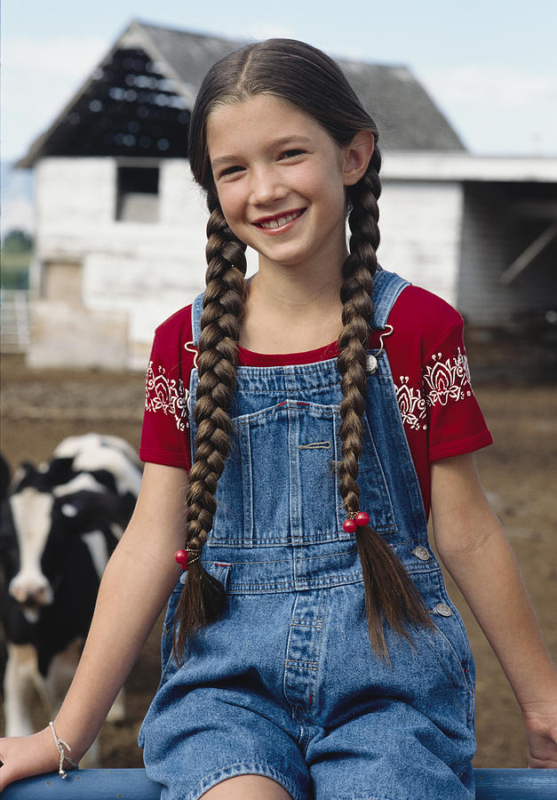 A caucasian girl in braided hair sits on a fence at a farm Photograph by Photodisc