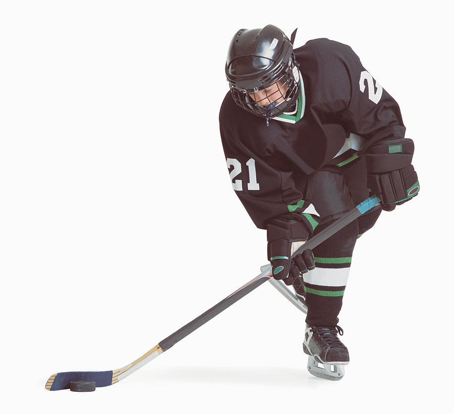 A Caucasian Hockey Player Wearing A Black Uniform Is Skating With His Stick About To Hit The Puck Photograph by Photodisc