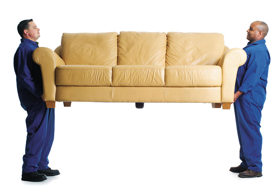 A Caucasian Male And An African American Male Mover Carry A Couch Together Photograph by Photodisc
