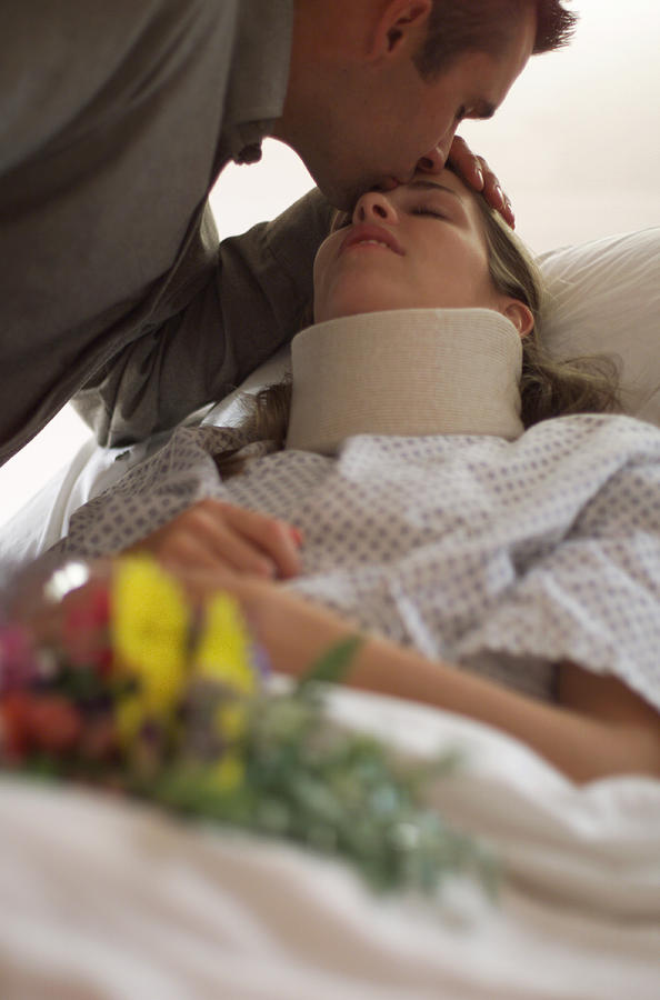 A Caucasian Man Brings Flowers To His Injured Wife As She Lays In A Hospital Bed Photograph by Photodisc