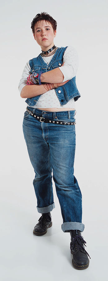 A Caucasian Teenage Girl With Spiked Hair And A Studded Belt Is Wearing Jean Pants And Vest As She Stands With Arms Folded And Frowns At The Camera Photograph by Photodisc