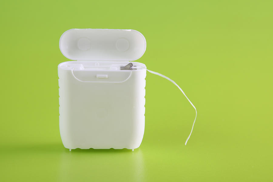 A close-up of a dental floss container on bright green Photograph by Dorioconnell