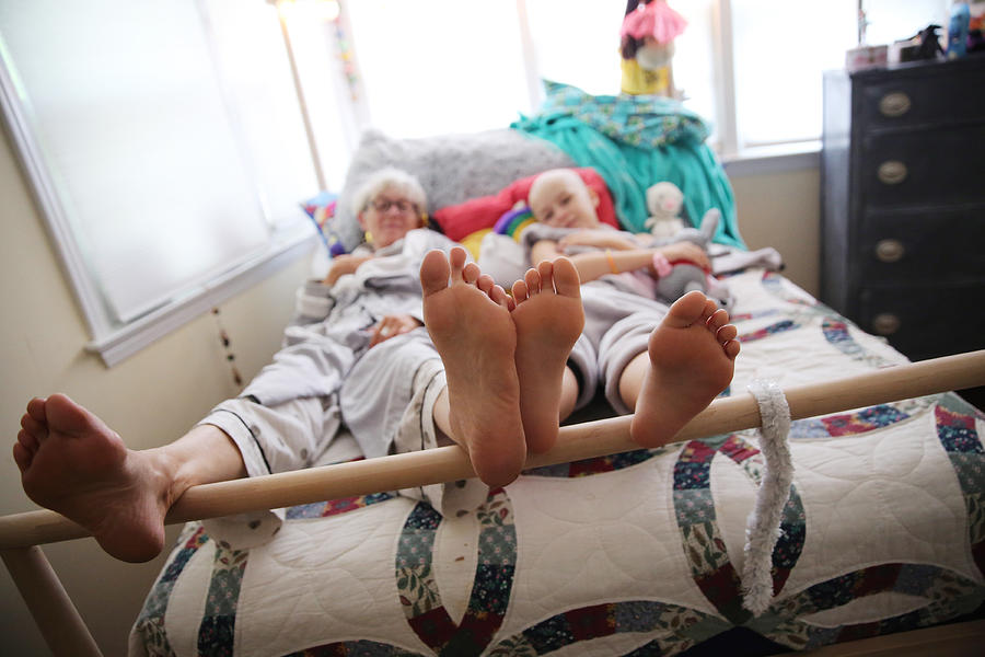 A close up of feet from an elderly woman and a young girl, with cancer, lay in bed. Photograph by Mireya Acierto
