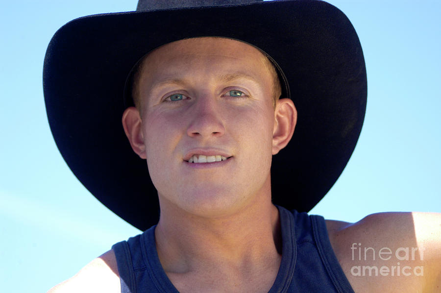 A close-up portrait of a young, blond cowboy with nothing but the sky in the backdrop. Photograph by Gunther Allen