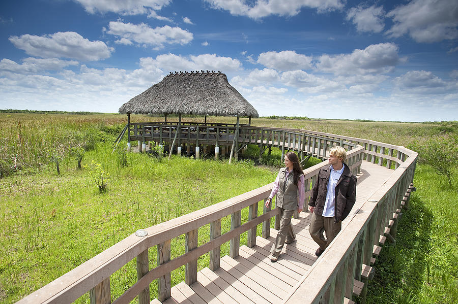 A couple enjoys a stroll along a wooden walkway in the Everglades National Park, Florida. Photograph by Corey Rich