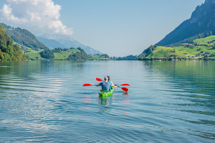 A couple paddling on Lungernsee lake Lungern in Switzerland between the mountains alps landscape on a summer day Photograph by Soblue.weina@gmail.com
