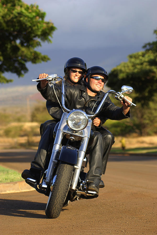 A couple rides their motorcycle on a curvy road toward the viewer. Photograph by Thinkstock