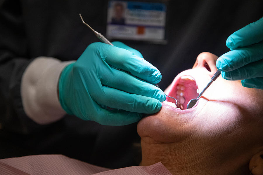 A Dentist Wearing Surgical Gloves Uses a Loupe Light to Examine the Teeth of a Female Patient in Her Sixties in a Dental Clinic Photograph by Hoptocopter