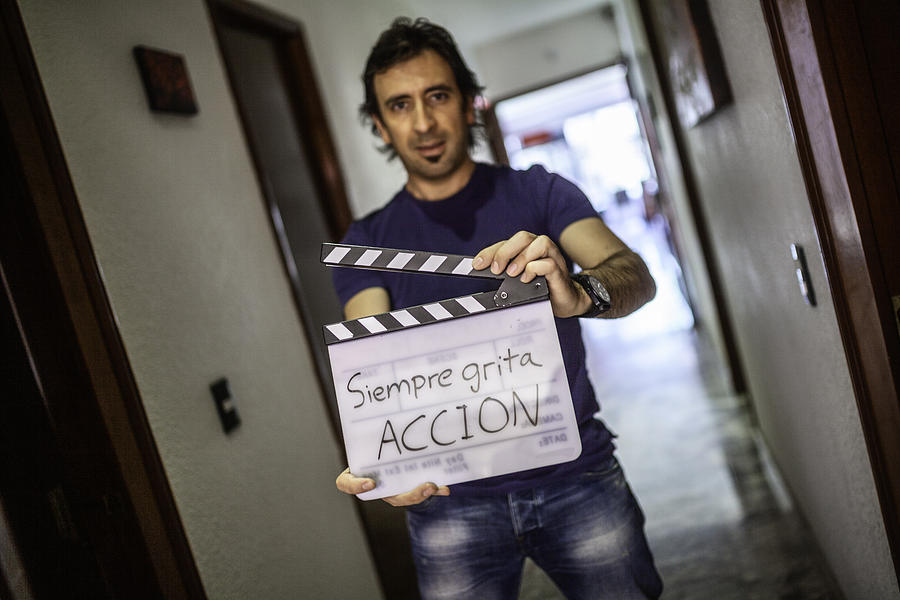 A director is holding a calpboard and telling all to scream action Photograph by ©fitopardo