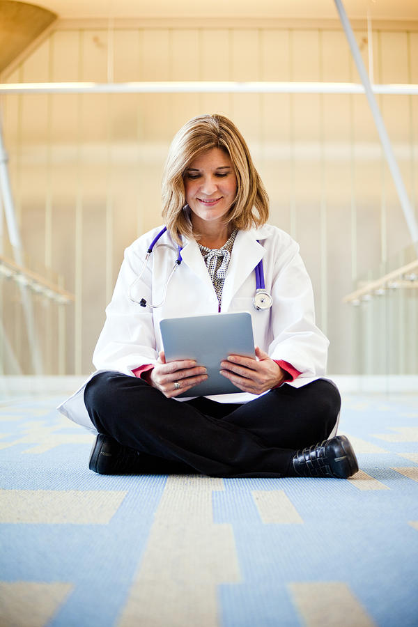 A doctor holding a tablet device inside a hospital Photograph by Adam Hester