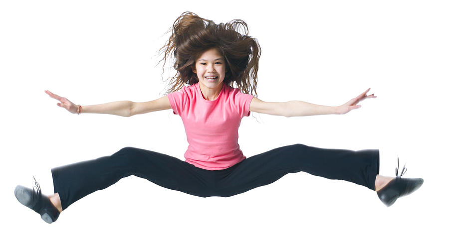 A Female Asian Child In Black Pants And A Pink Shirt Jumps Up And Kicks Out Her Legs Photograph by Photodisc