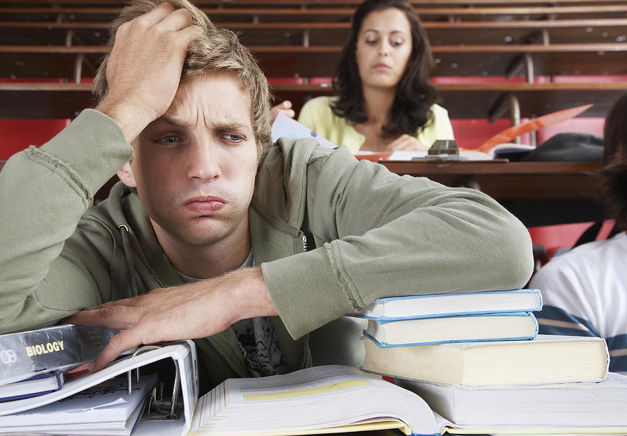 A frustrated male in a classroom with two students in background Photograph by OJO Images