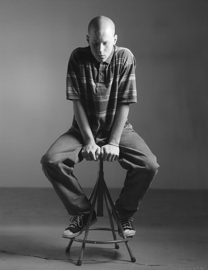 A full body portrait of a bald caucasian man who sits on a stool  looking down Photograph by Photodisc