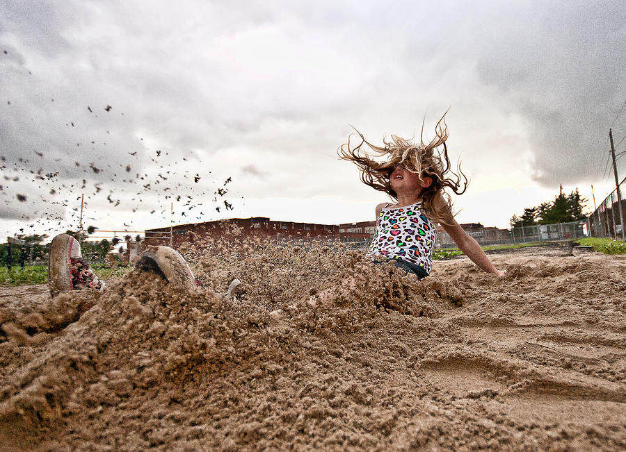 A girl landing in a sandy long jump pit Photograph by Krista Long