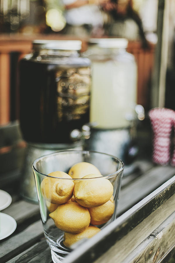 A Glass Bowl Filled With Small Lemons Beside Beverage Containers Photograph by Melody Davis / Design Pics