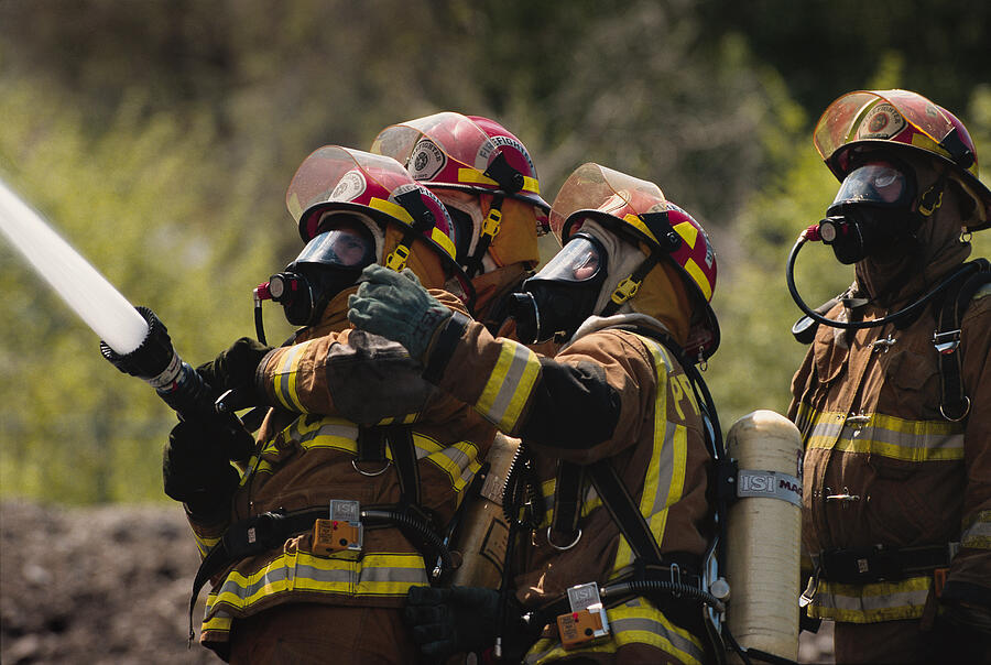 A Group Of Firefighters In Full Gear Dowse A Fire With A Firehose Photograph by Photodisc