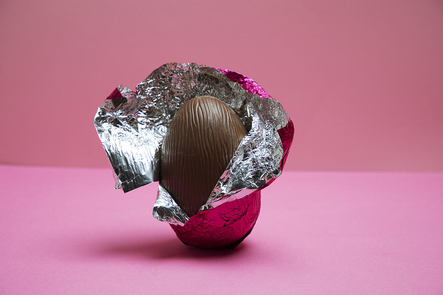 A half unwrapped Easter egg on a pink background. Photograph by Betsie Van der Meer