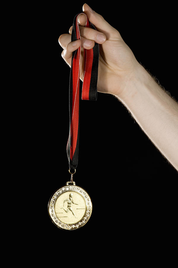 A hand holding a gold medal Photograph by Adam Burn