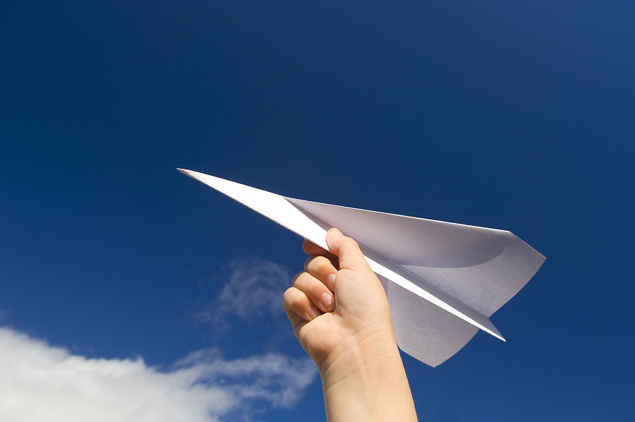 A hand holding a paper plane with the view of the sky Photograph by Northlightimages